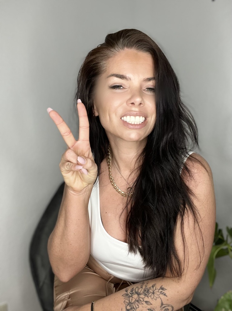 Mariane Michels lacht in die Kamera und zeigt das Peace-Zeichen